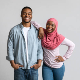 Family photo of cheerful loving african american young muslim couple posing on grey studio background. Beautiful black man and woman in hijab hugging and smiling at camera, relationships concept
